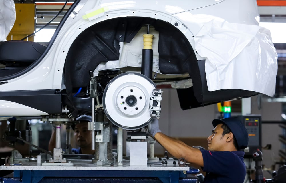 Worker assembles cars at automobile assembly line production plant.