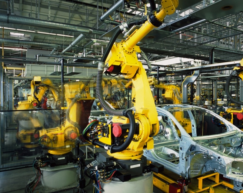 A robotic arm within a manufacturing facility in Mexico works to operate on the frame of an automotive vehicle.