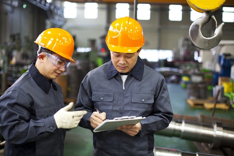 Picture of two Chinese factory workers standing and talking inside a manufacturing facility in China